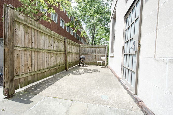 Mudge House Patio - cement patio surrounded by wood fence with a charcoal grill and a chair